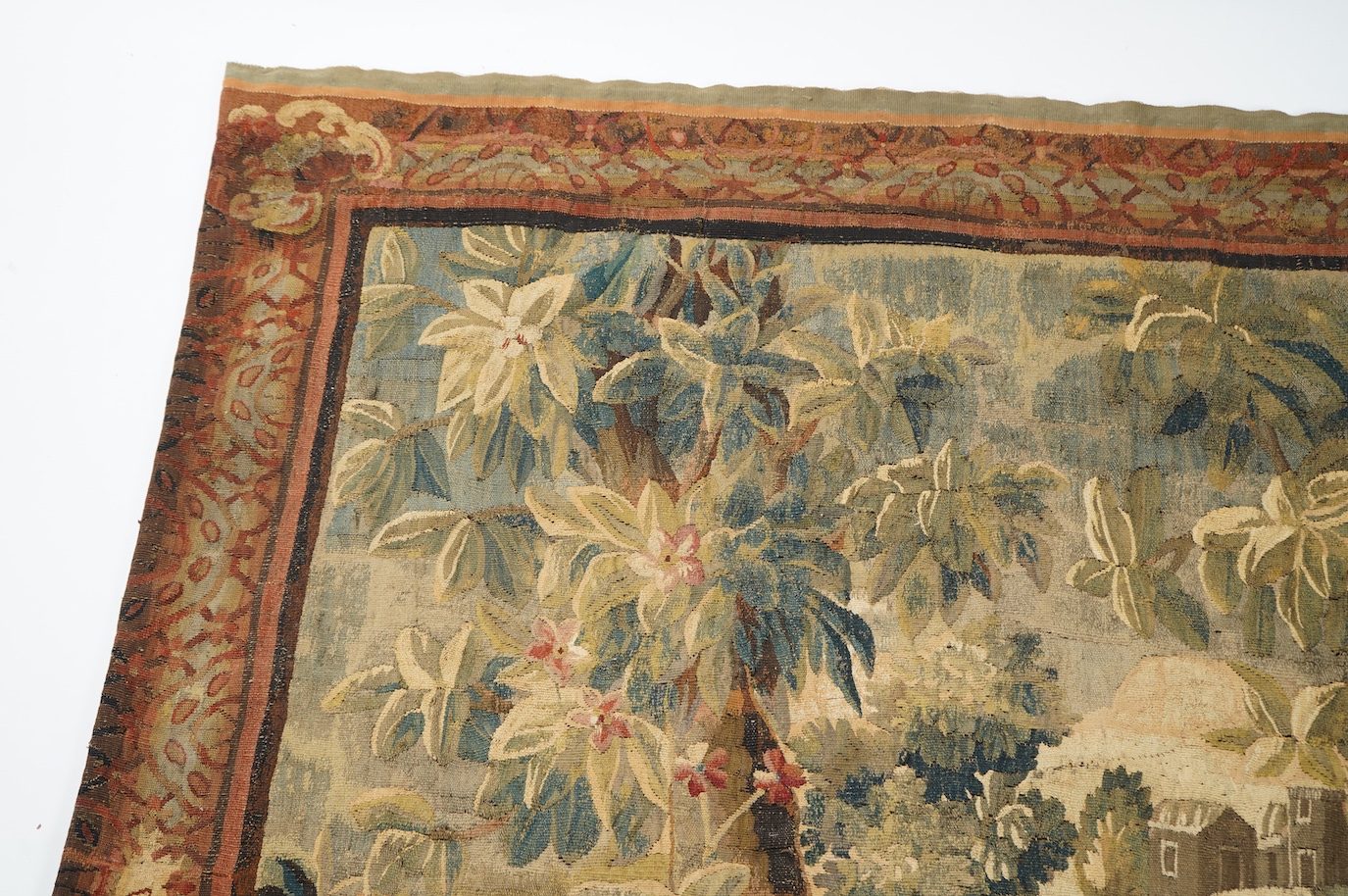 A mid to late 18th century French Aubusson tapestry of a bird, possibly a heron, within a tree lined verdure garden scene to a chateaux, with an ornate rust coloured contrasting tapestry border.201cm x 170 cm. Condition